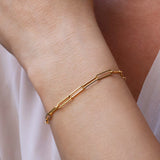 Gold chain link bracelet on a wrist with a blurred background