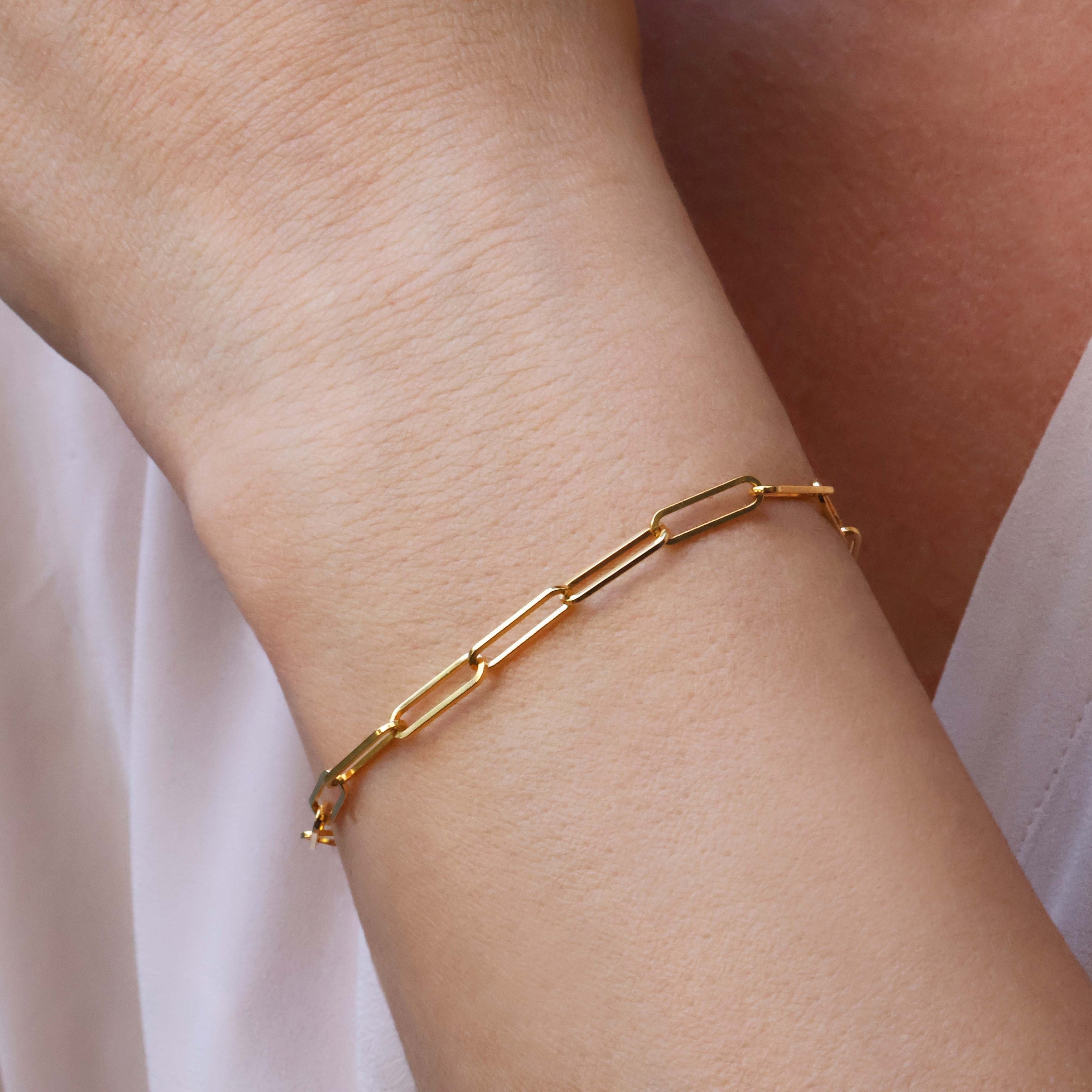 Gold chain link bracelet on a wrist with a blurred background