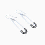 Silver safety pin earrings on a white background